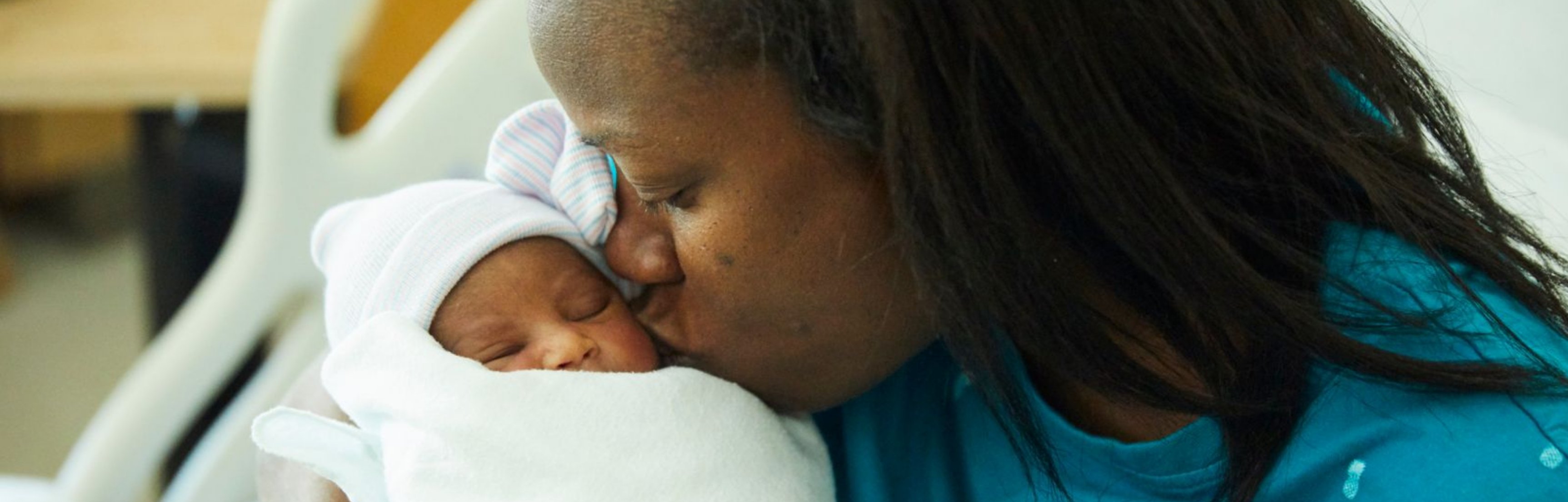 Foto de una madre besando a su hijo recién nacido
