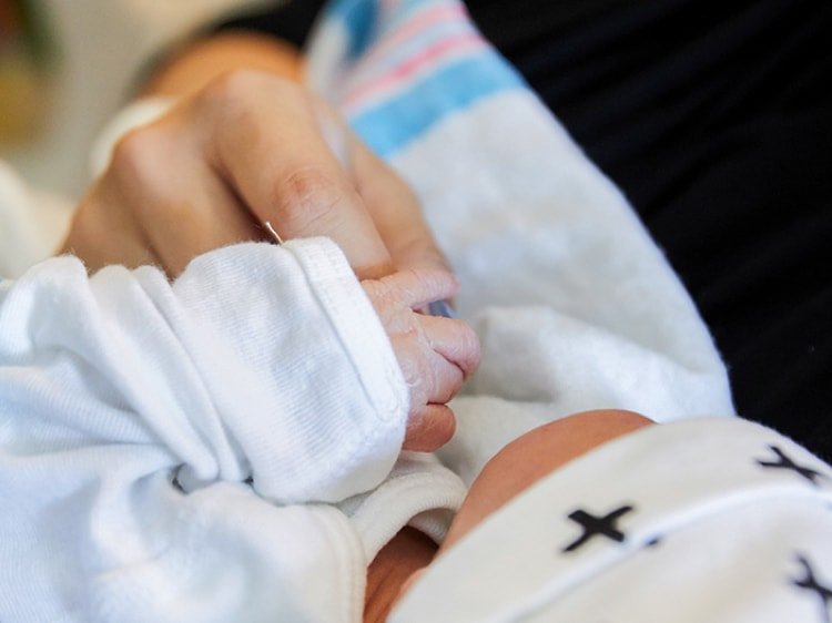 Primer plano de un bebé recién nacido agarrando un dedo