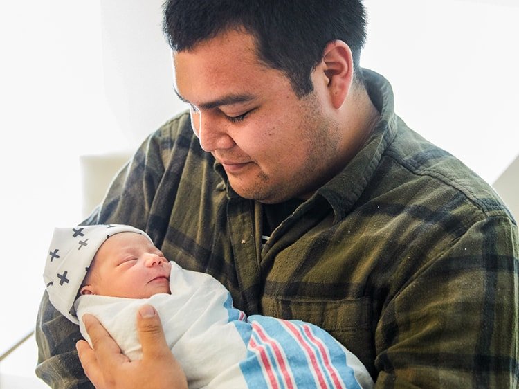 Papá latino sosteniendo a su bebé recién nacido